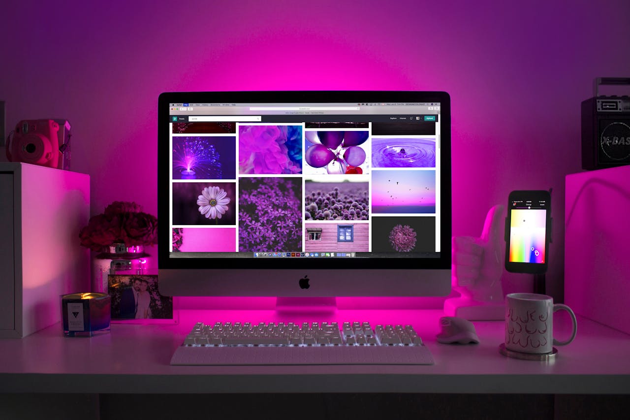 About Modern desk setup with neon lighting and a desktop computer displaying colorful images.